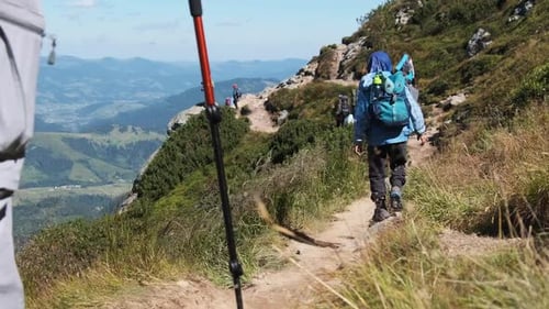 Group of Tourists and Children with Backpacks Go Down on Stone Trail in Mountain