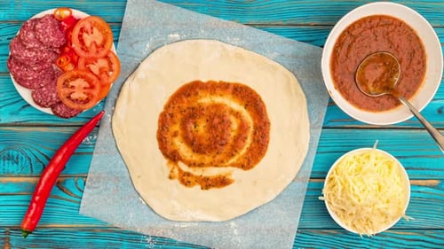 Draufsicht auf das Kochen von Pizza mit Zutaten auf blauem Holzuntergrund.