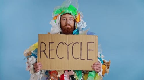 Man Covered in Trash Holding Recycle Sign
