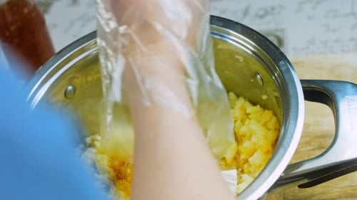 Hands Mixing Mashed Potatoes with Cheese in Pot
