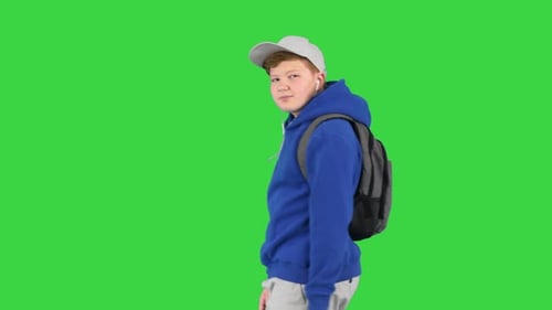 Handsome School Boy Walking By While Listening To Music on a Green Screen Chroma Key