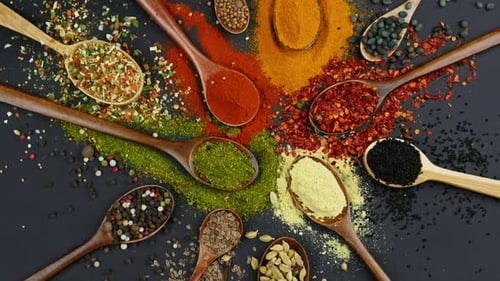 Dry Colorful Spices in Spoons and Bowls with Fresh Seasoning on Dark Background Top View