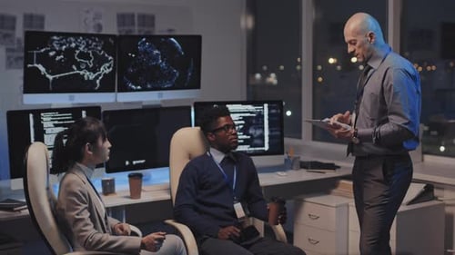 Team Discussing Computer Code in Modern Office at Night