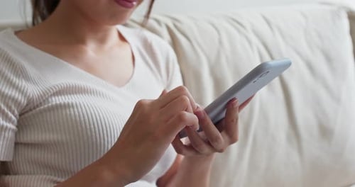Woman Using Smartphone Device on Comfortable Couch
