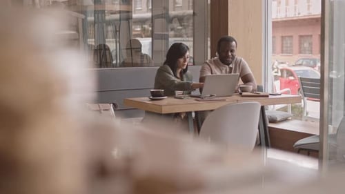 Multiethnic Colleagues Discussing Project in Cafe