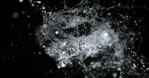 L'eau tombe et éclabousse sur fond noir, ralenti 4K