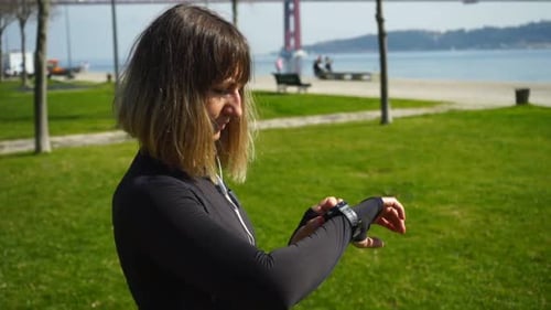 Sportliches Mädchen in Ohrhörern mit Smartwatch Outdoor