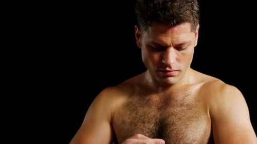 Muscular Man Wrapping Hands for Boxing Training