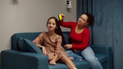 Woman Brushing Young Girl's Long Hair Indoors