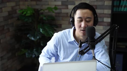 Young Adult Businessman Recording Podcast Talk Show at Home Studio with Computer Laptop on Table