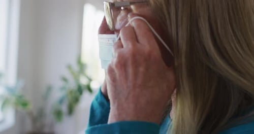 Woman Puts on Medical Face Mask at Home