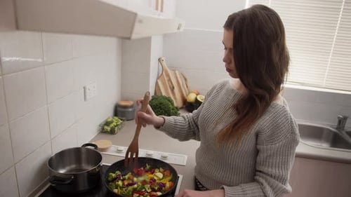 Young Woman Cooking Vegetables in Bright Kitchen
