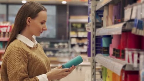 A Young Cheerful Woman Buys Candles in a Store