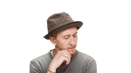 Junger gutaussehender Mann mit Hut denkt darüber nach, auf weißem Hintergrund zu lächeln