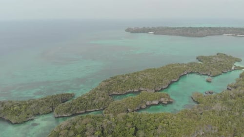 Aerial: flying over tropical sea pristine coastline rainforest turquoise lagoon