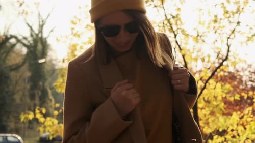 Smiling Woman in Coat and Sunglasses Has Fun in Forest