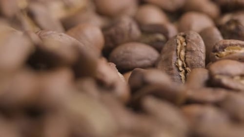 Super close up of roasted brown coffee beans, spinning camera shot