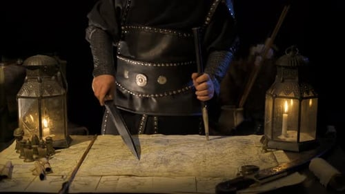 Commander working on map with sword in hand.