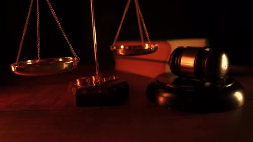 Imagem aproximada de um antigo martelo de juiz e uma balança da justiça