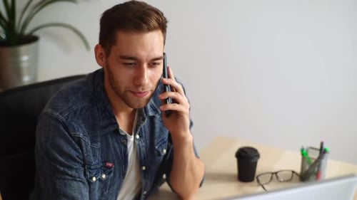 Closeup Top View of Cheerful Handsome Business Man Talking Phone Sitting at Desk with Laptop at