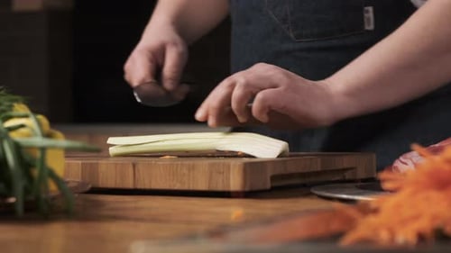 Chef in der Restaurantküche schneidet Sellerie mit einem scharfen, glänzenden Messer