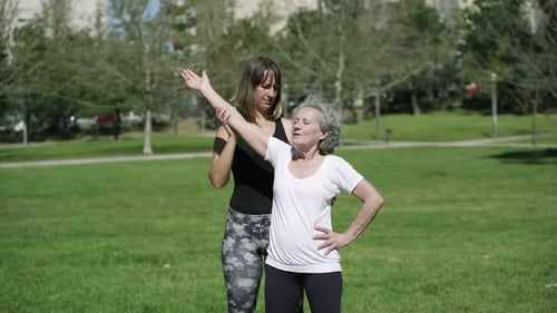 Senior Woman Stretching with Help in Park