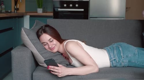 Woman Relaxing on Couch with Smartphone at Home