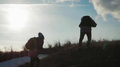 People Hike Up Hill with Backpacks in Sunlight