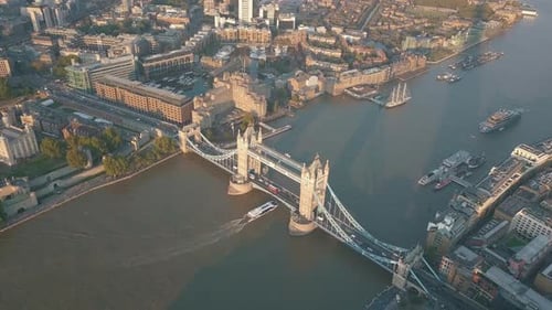 Boat on Thames River passing under Tower Bridge in London at Sunset or Sunrise, Aerial Slide Left Es