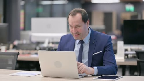 Businessman Talking on Video Call on Laptop in Office
