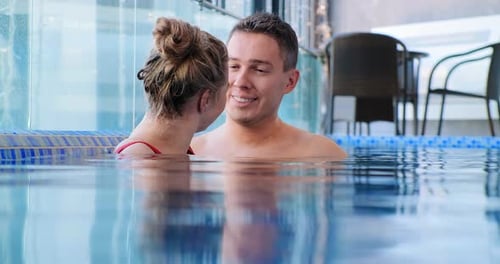 Blonde Smiles Submerged in Blue Swimming Pool Water Near Man