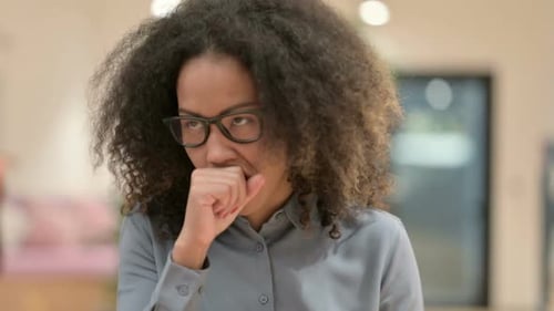 Young Woman Coughing into Fist Indoors