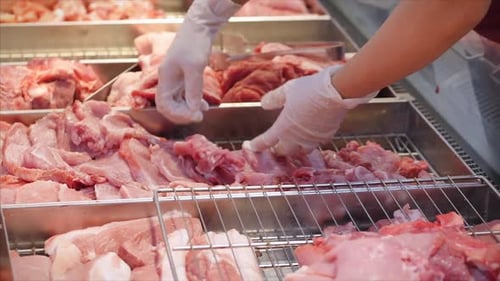 Female Saleswoman or Merchandiser in a Supermarket or Market Puts Meat on a Baking Tray, Beautifully