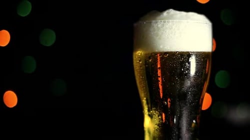 Glas mit kaltem Bier auf schwarzem Hintergrund