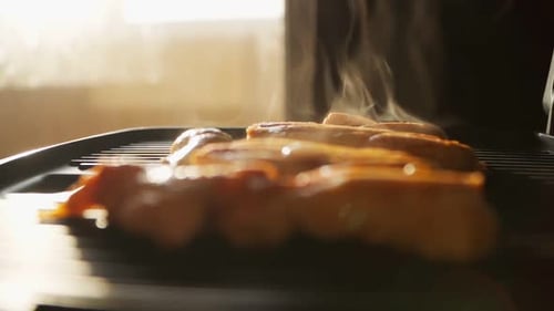 Cooking fried chicken meat on an electric grill. Beautiful sunlight on the background