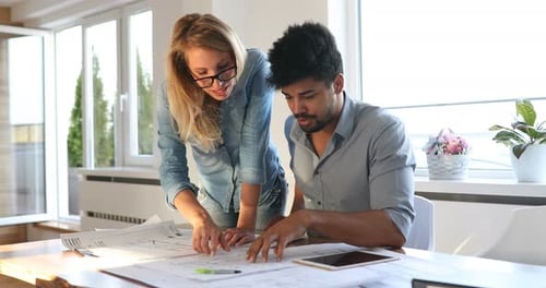 Architects Collaborating on Building Plans in Office