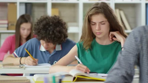 Students Writing at Desks in Classroom