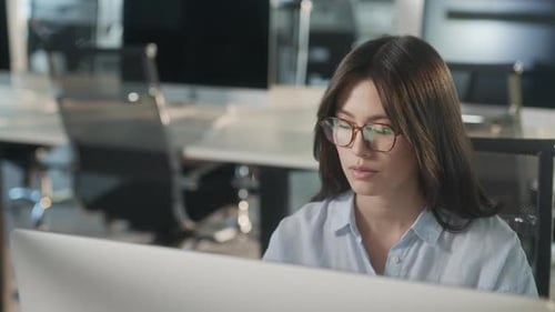 Junger asiatischer Marketingspezialist arbeitet an einem Laptop in einer geschäftigen kreativen Büroumgebung