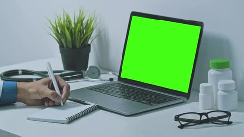 Doctor Taking Notes with Laptop and Green Screen