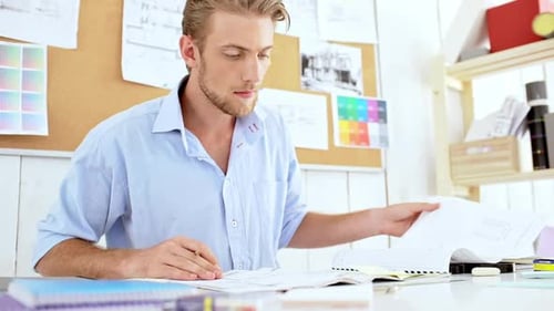Man Working on Blueprints in a Bright Office