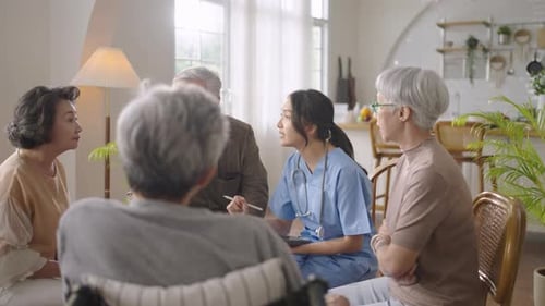 senior people sit in a circle in a nursing home and listen to nurse during a group elderly therapy