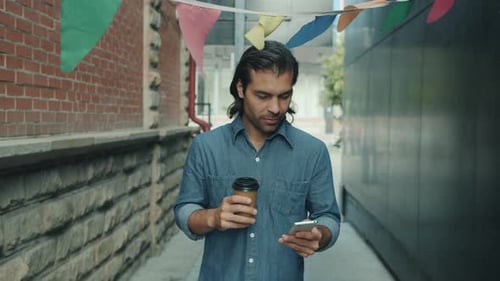 Man Walking and Using Phone with Coffee in City
