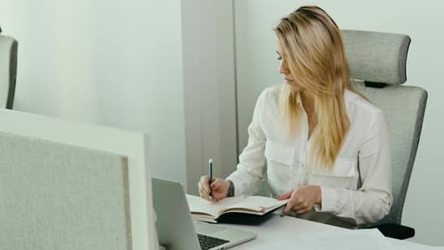 Woman Working at Desk Taking Notes