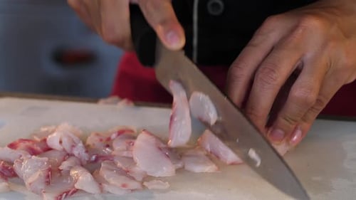Chef Dicing Raw Fish on Cutting Board