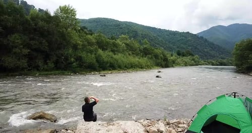 Canadian Mountain River Man Resting Sitting By a Stormy River