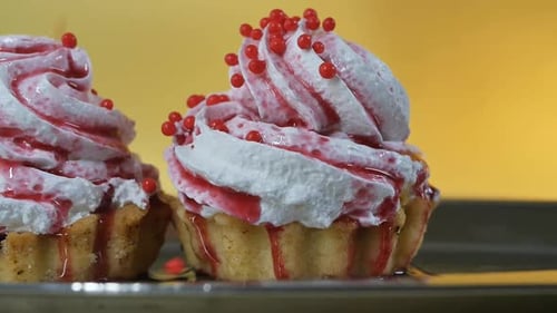 Zwei Kuchen mit Sahne bestreuen, mit süßem Beerensirup übergossen, mit rundem Gebäck, rote Dekorationskugeln
