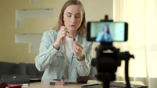 Mujer bloguera de belleza filmando un tutorial de maquillaje en cámara, mujer influyente que transmite cosméticos en vivo
