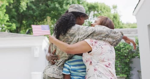 Military Woman Returns Home, Embracing Family with Flags