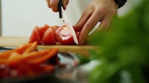 Person Slices Ripe Tomato on Cutting Board