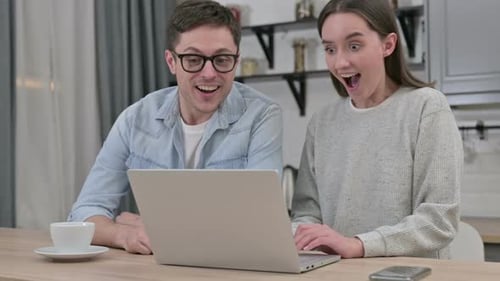 Couple Celebrating Success Together on Laptop